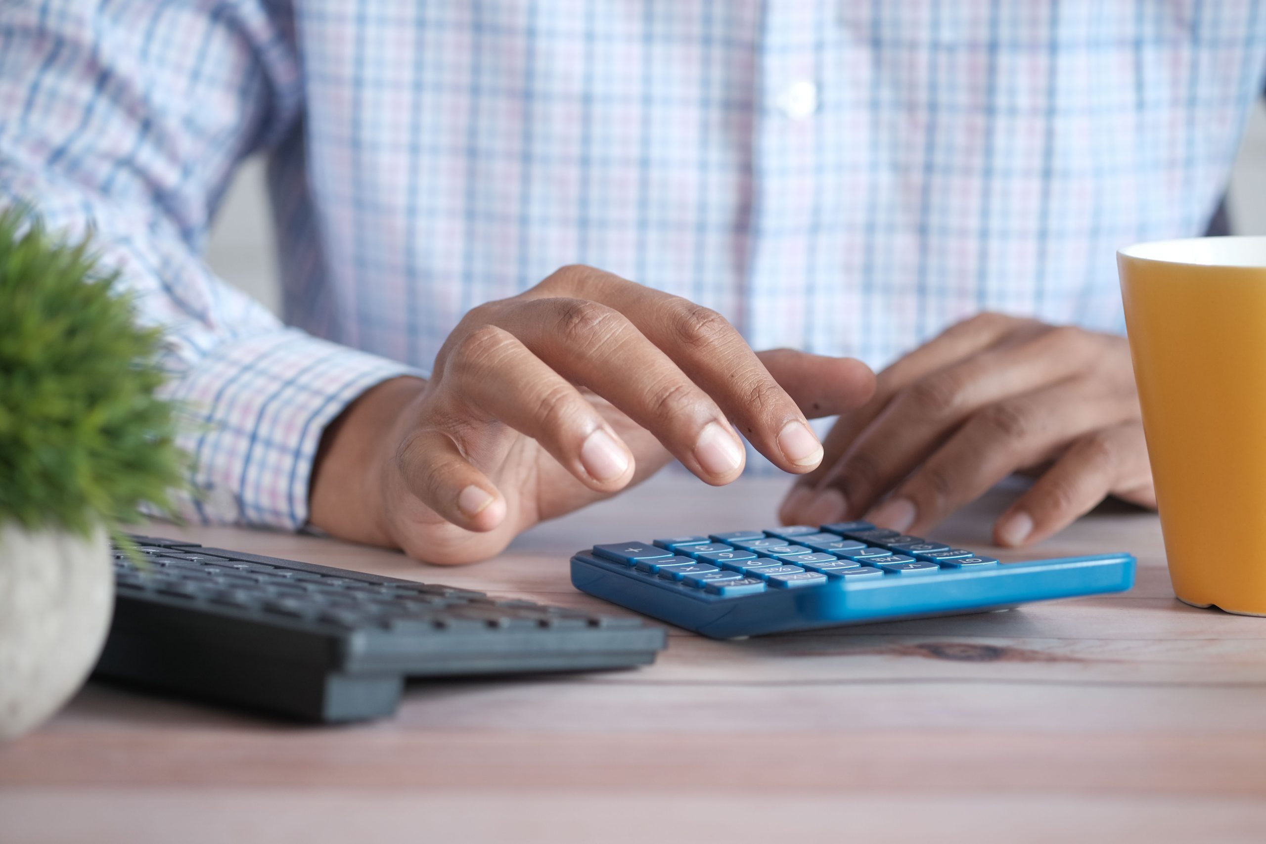 Personne utilisant une calculatrice bleue sur un bureau en bois