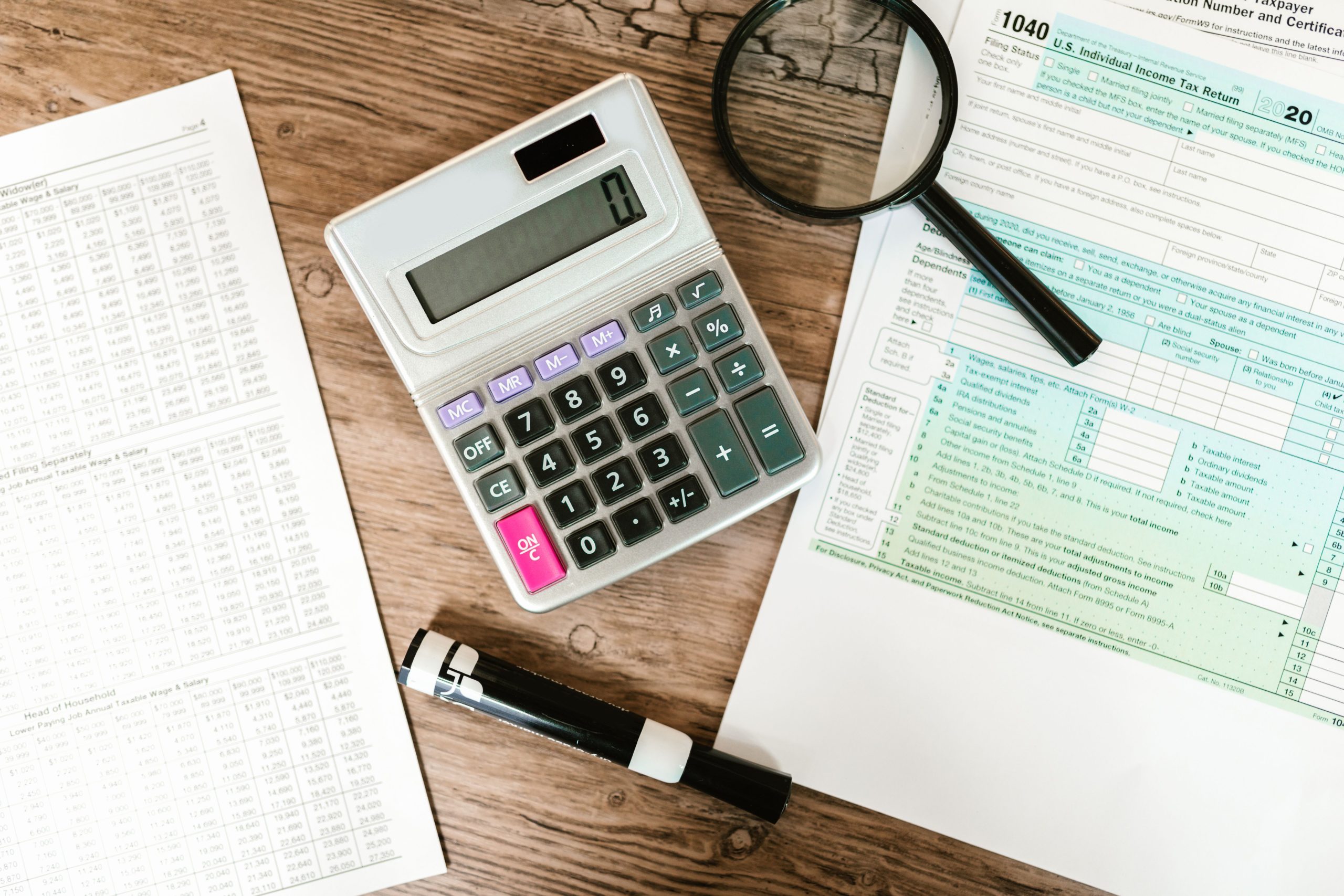 Formulaires fiscaux, calculatrice et loupe sur surface en bois